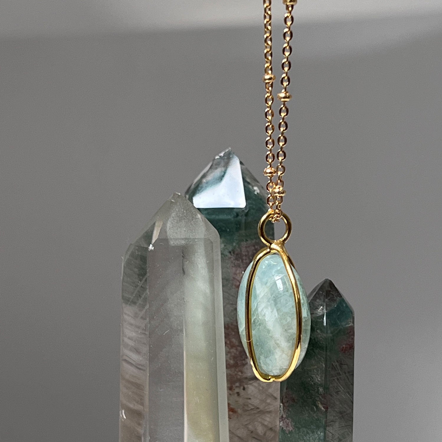 Gold plated Aquamarine necklace on a background of crystals