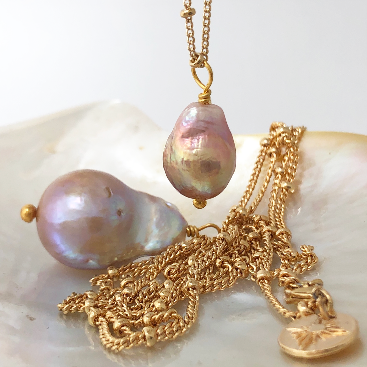Baroque Pear Pearl on Mini Biba Gold-Plated Chain with 2 other necklaces on a crystal bed