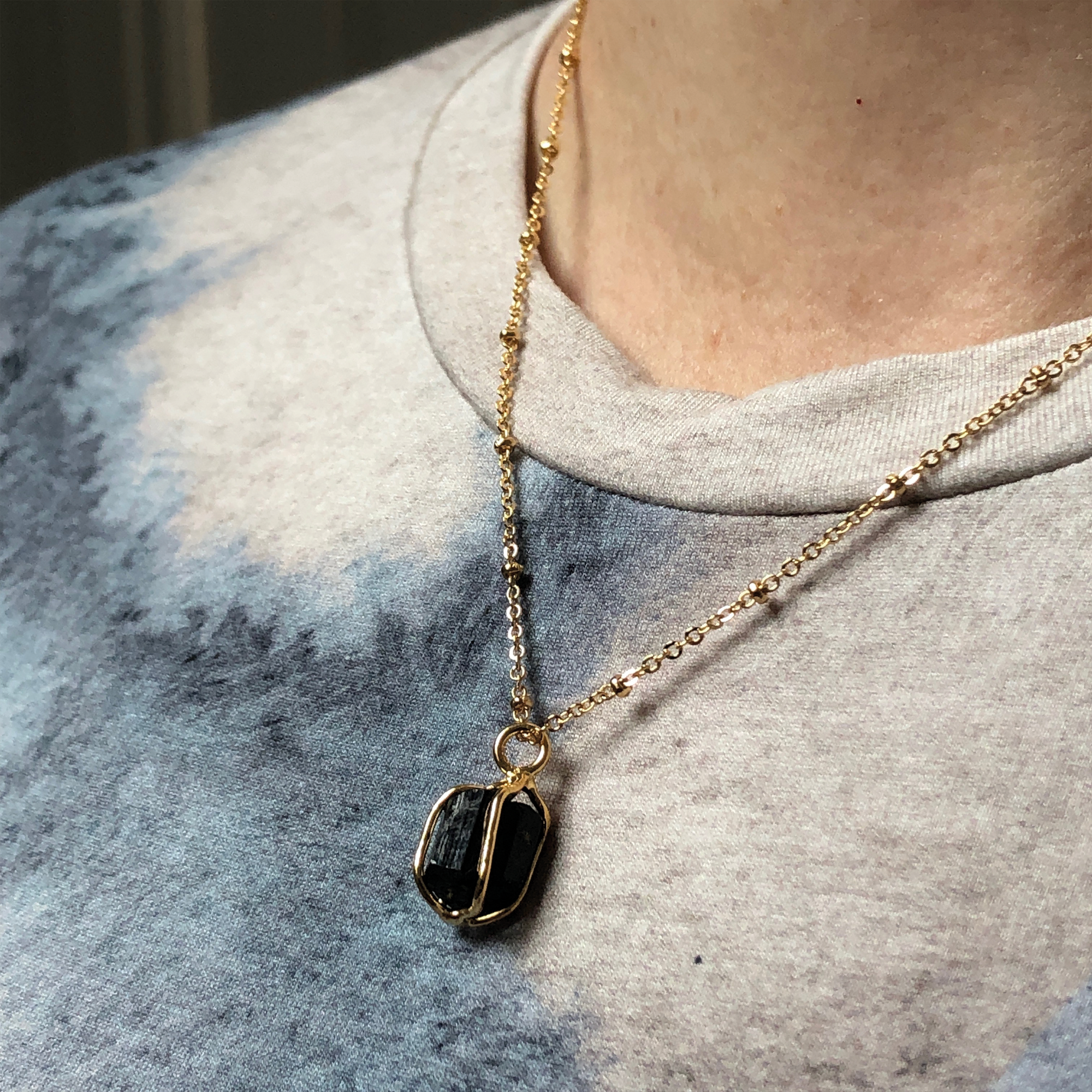 Black Tourmaline Pendant Raw Crystal Necklace worn on a grey and white multi-coloured sweater