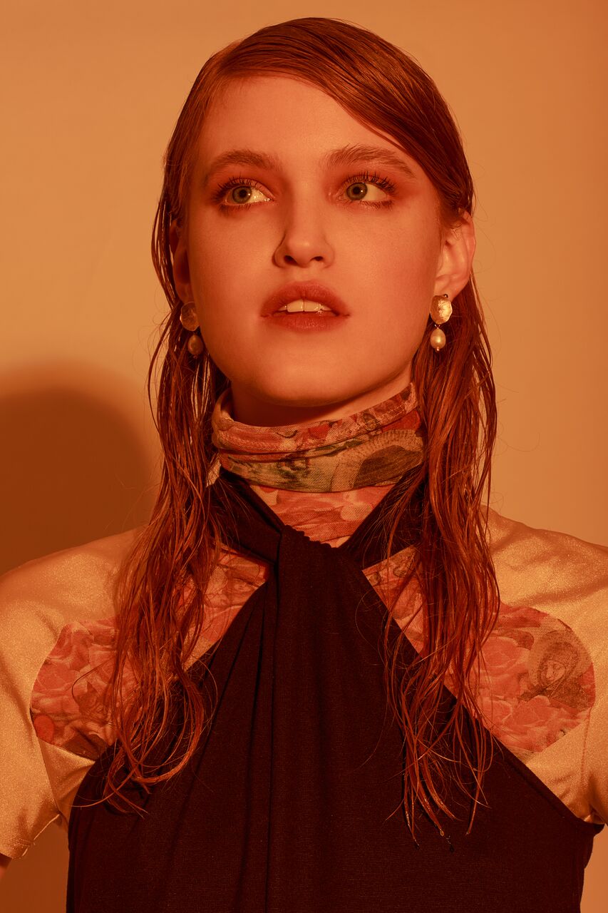 A model wearing beautiful 22ct gold-plated earrings with a flower design and coral freshwater pearls.