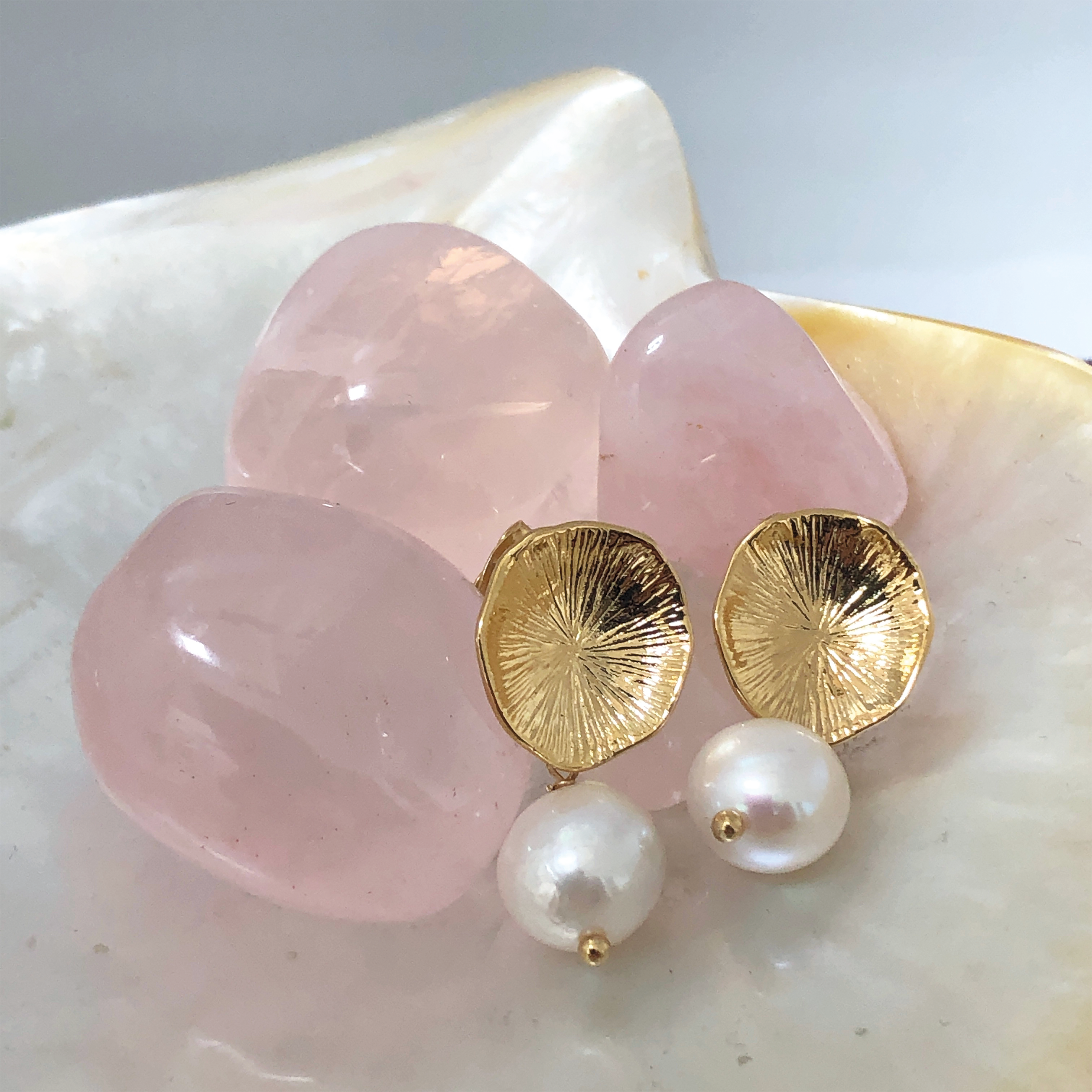 22ct gold-plated earrings with a flower design and coral freshwater pearls. with some crystals in the background