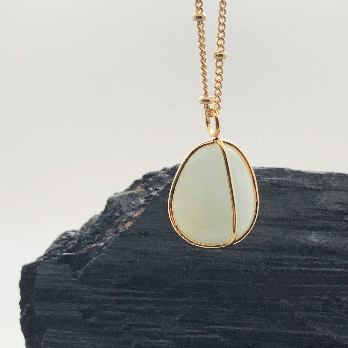 Gold plated Aquamarine necklace with a dark crystal in the background