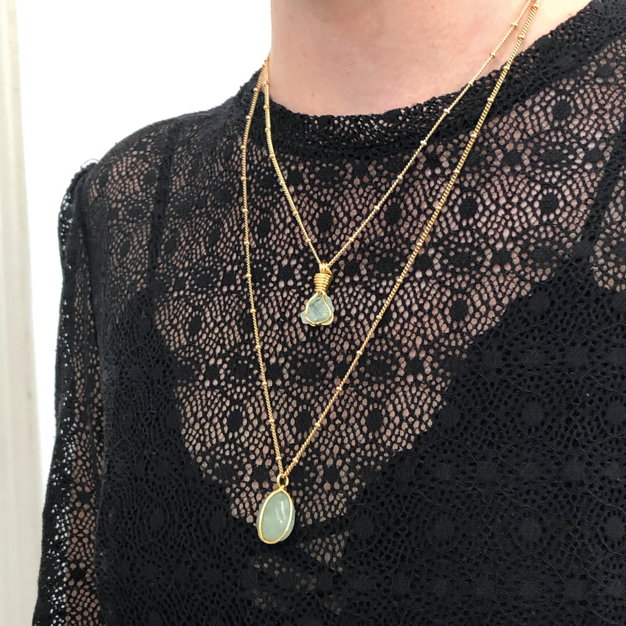 A perosn wearing 2 different aquamarine necklaces