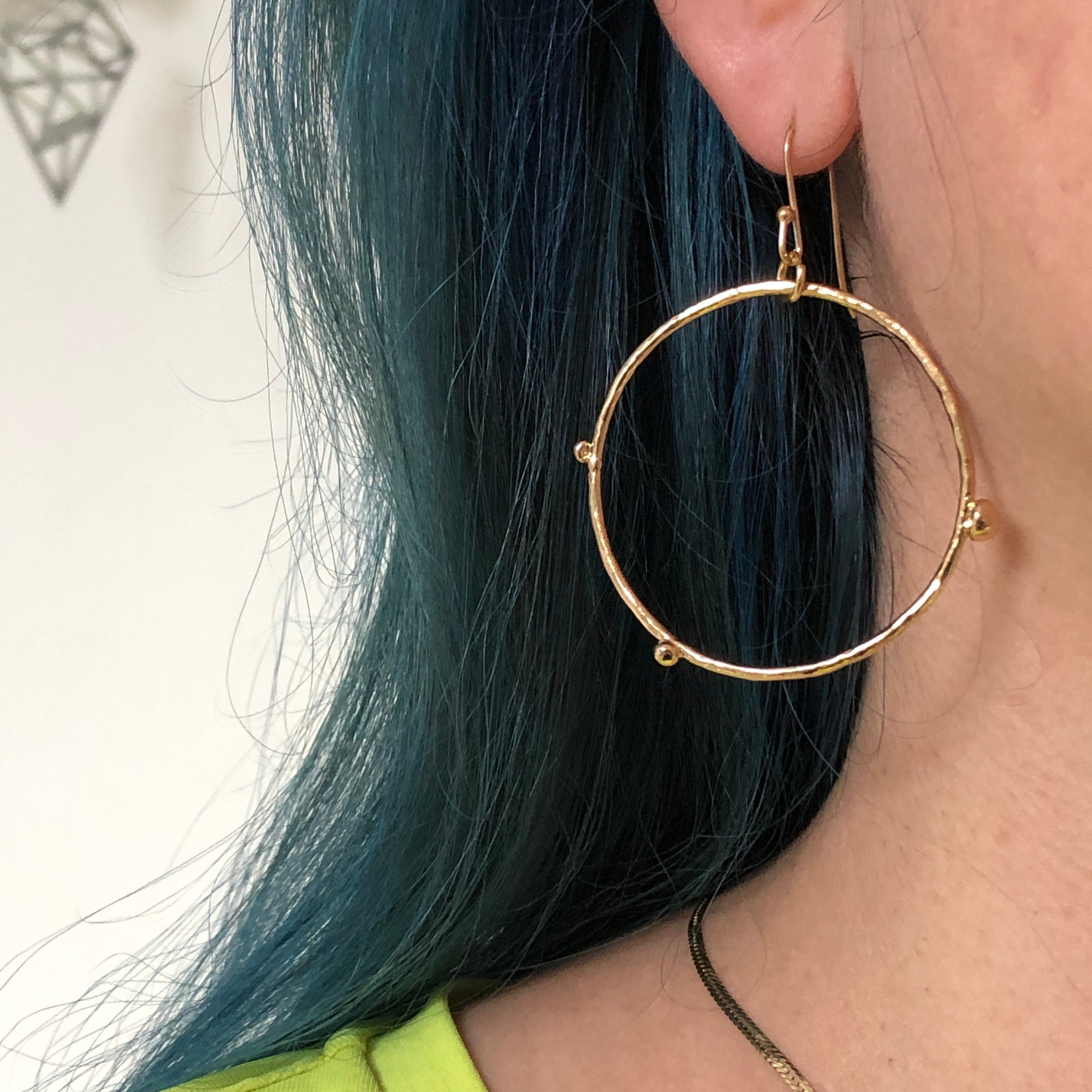 Close up of a model's ear wearing a gold-plated dot hoop earring