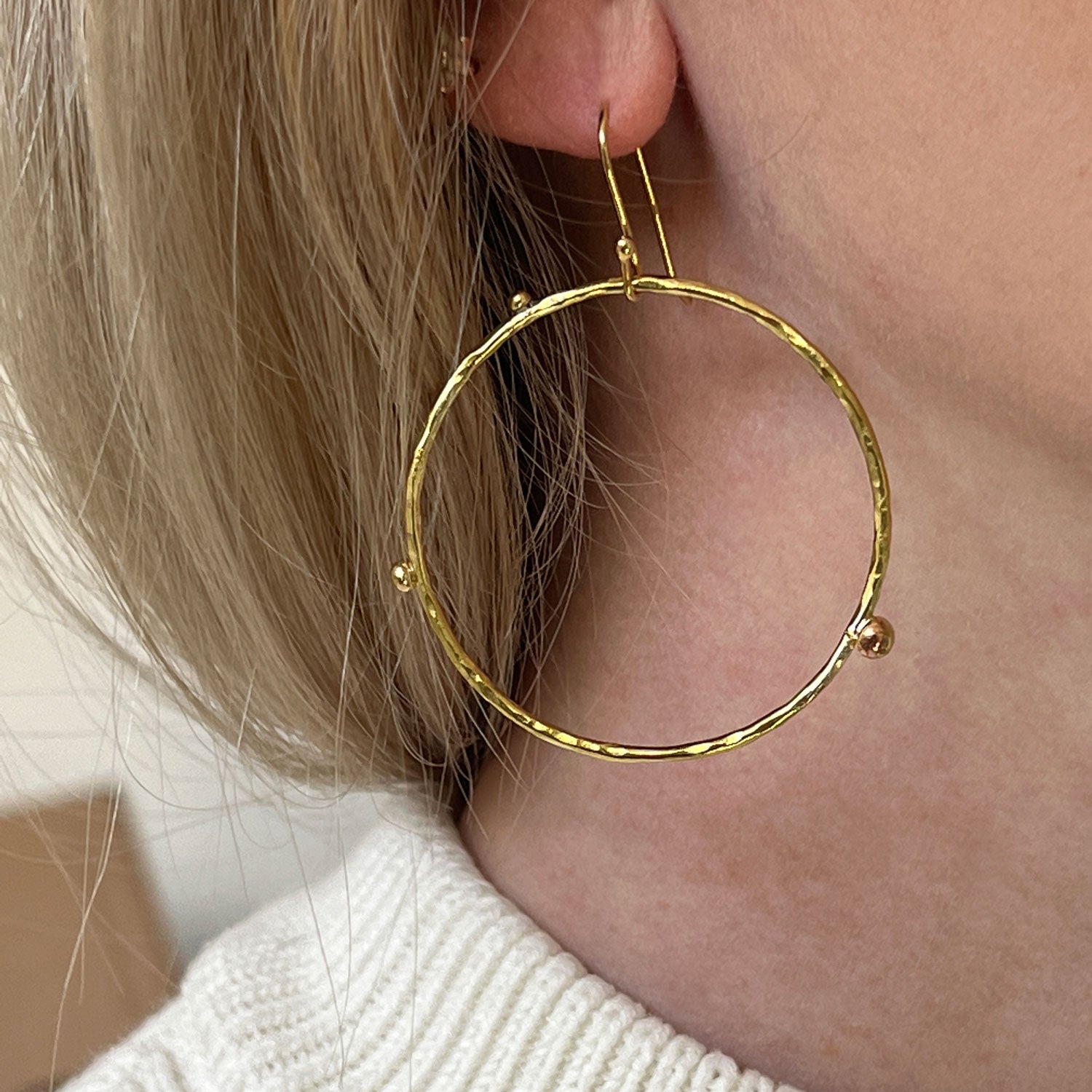 Close up of a model's ear wearing a gold-plated dot hoop earring