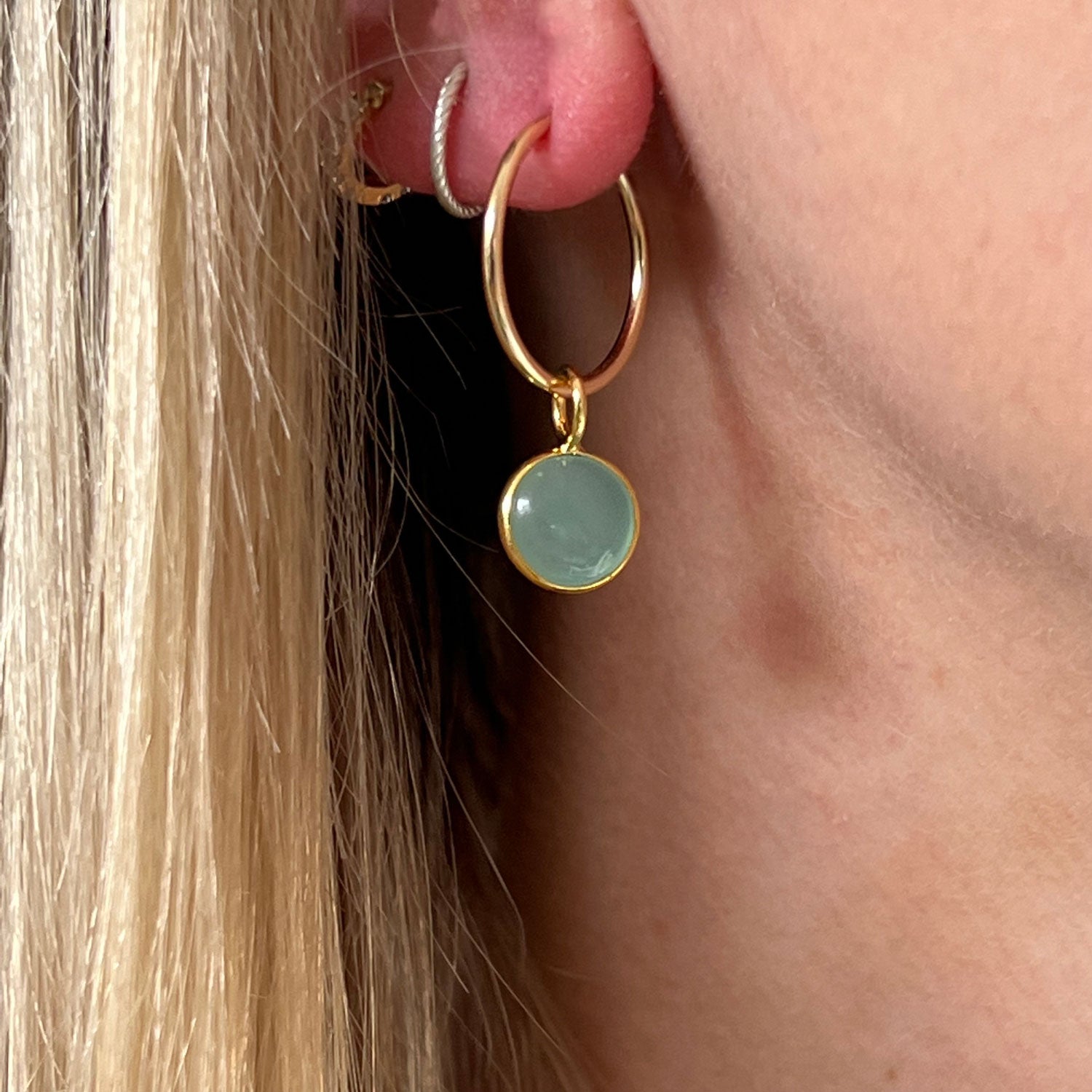 A close up of an aqua Chalcedony Gold Creole Hoop Earring in an ear