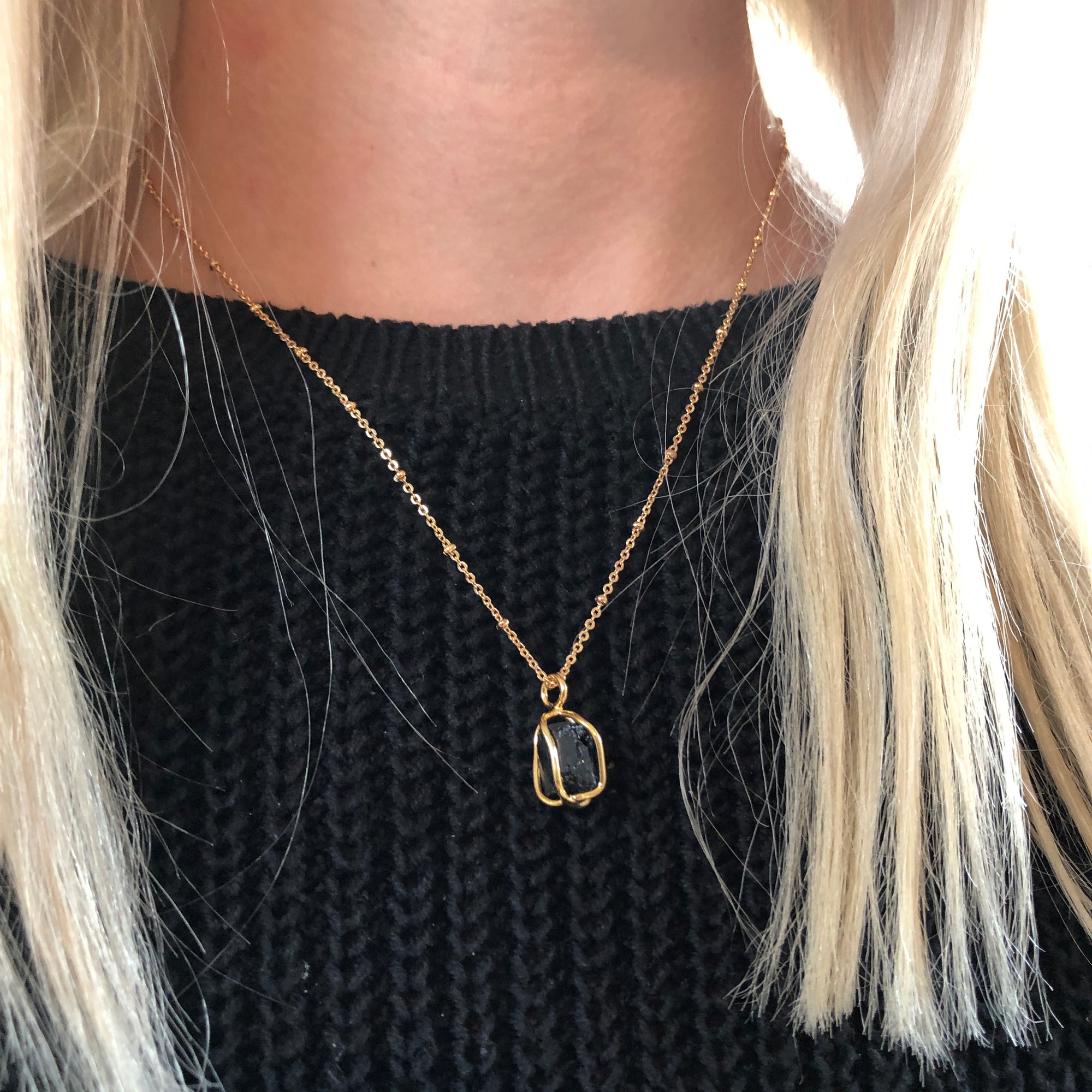 Black Tourmaline Pendant Raw Crystal Necklace worn on a black jumper