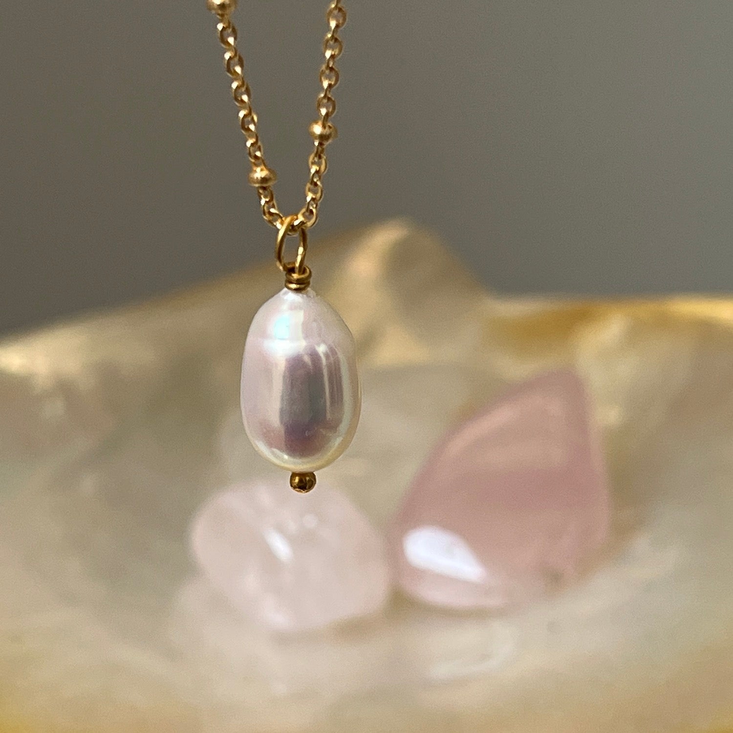 Gold-plated pearl drop necklace with crystals in the background