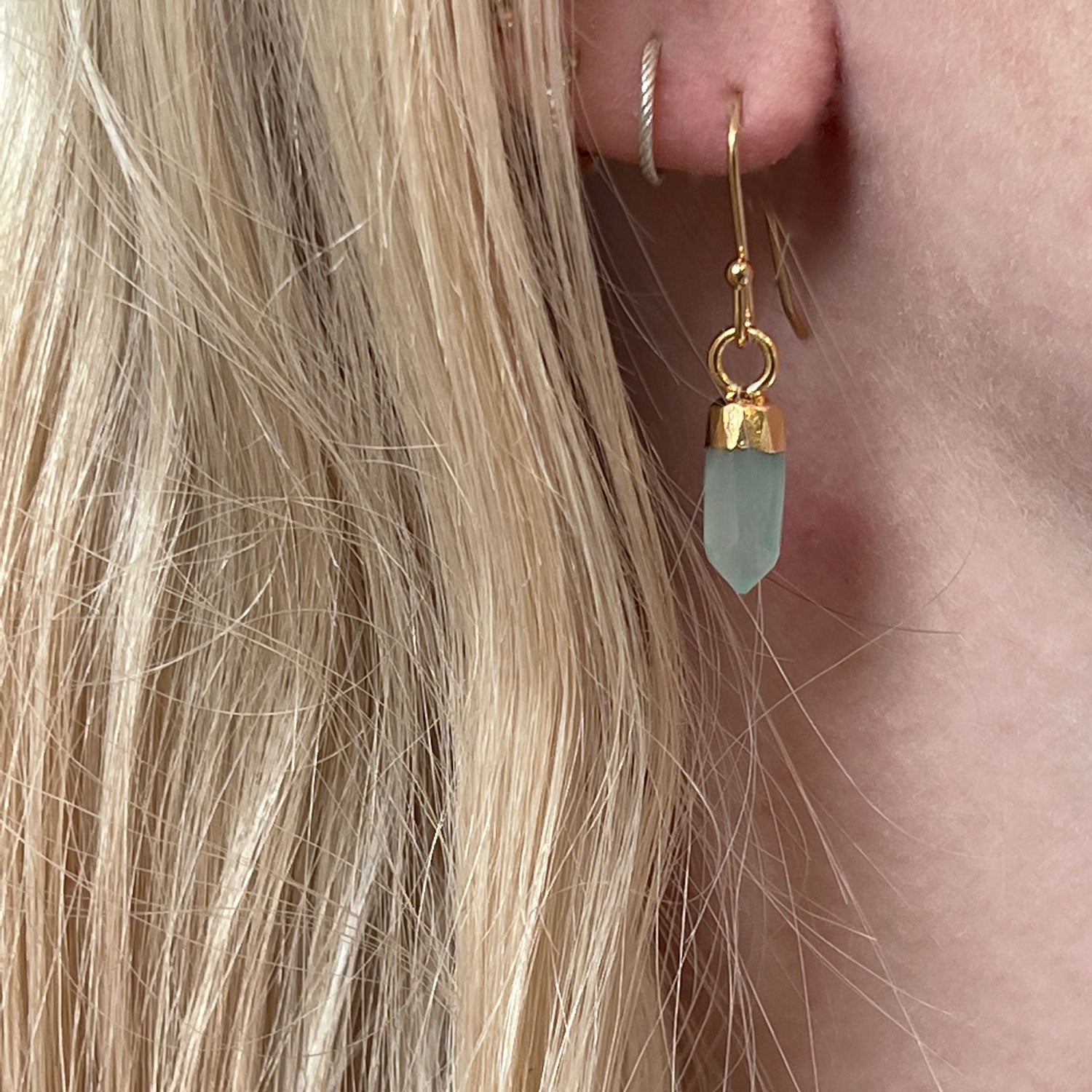 A close up of a model's ear wearing an aqua chalcedony crystal earring