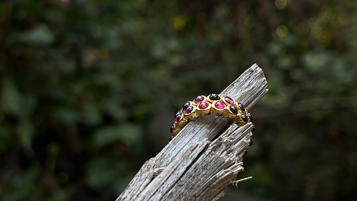Gold ring with gemstones on a wooden branch against a blurred natural background