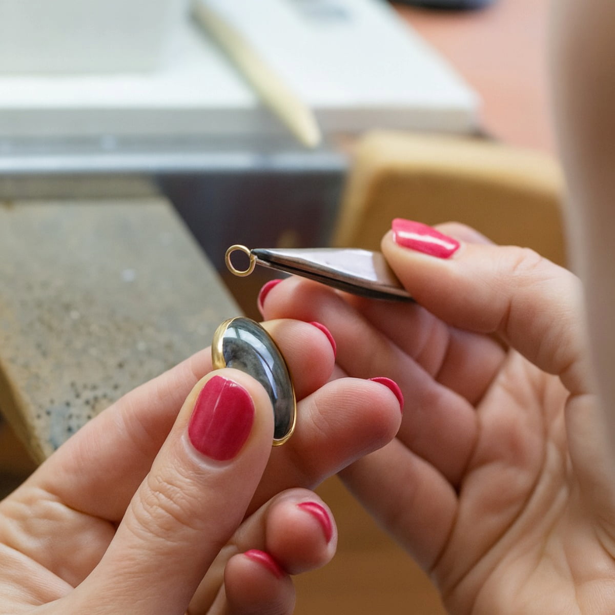 Person working on a delciate piece of jewellery with tweezers, blurred background
