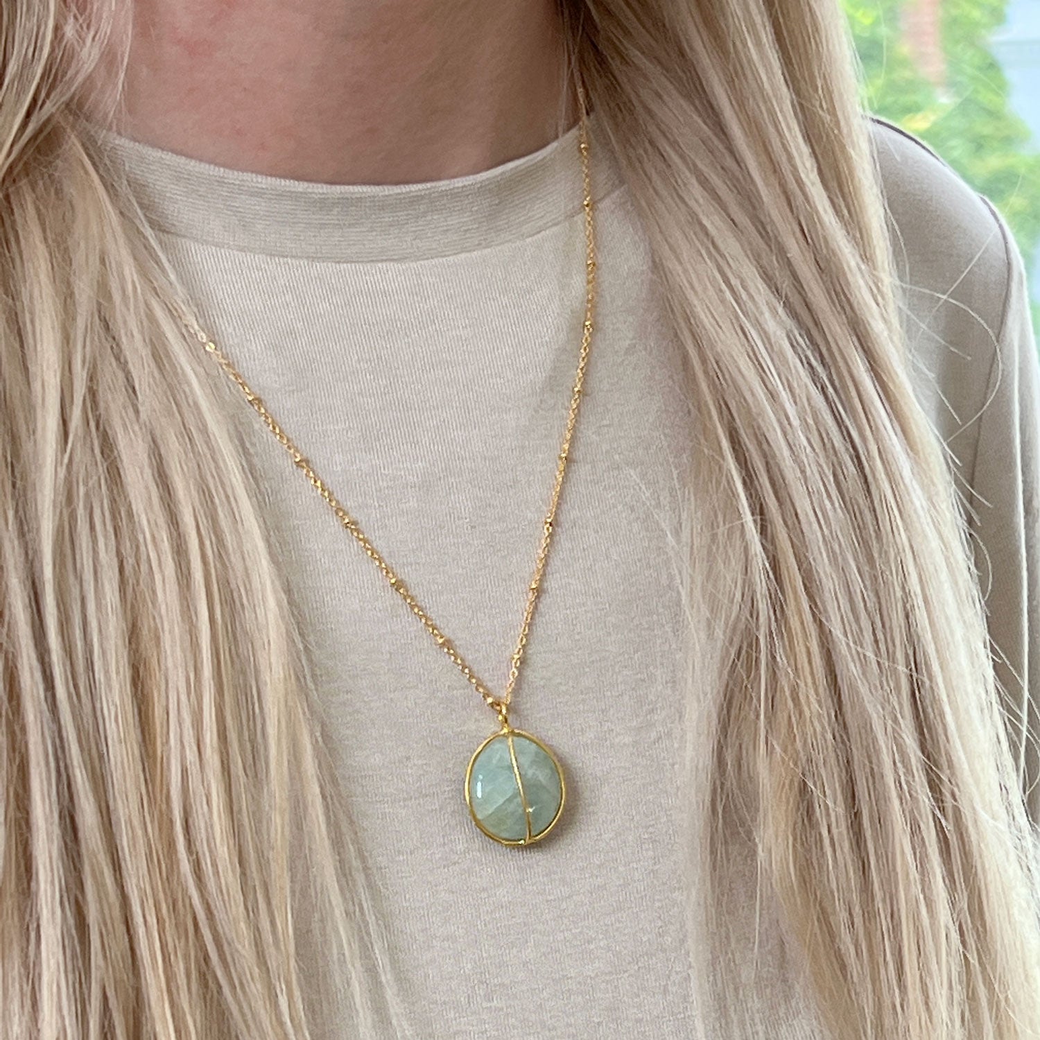 Gold plated aquamarine necklace worn against a cream sweater