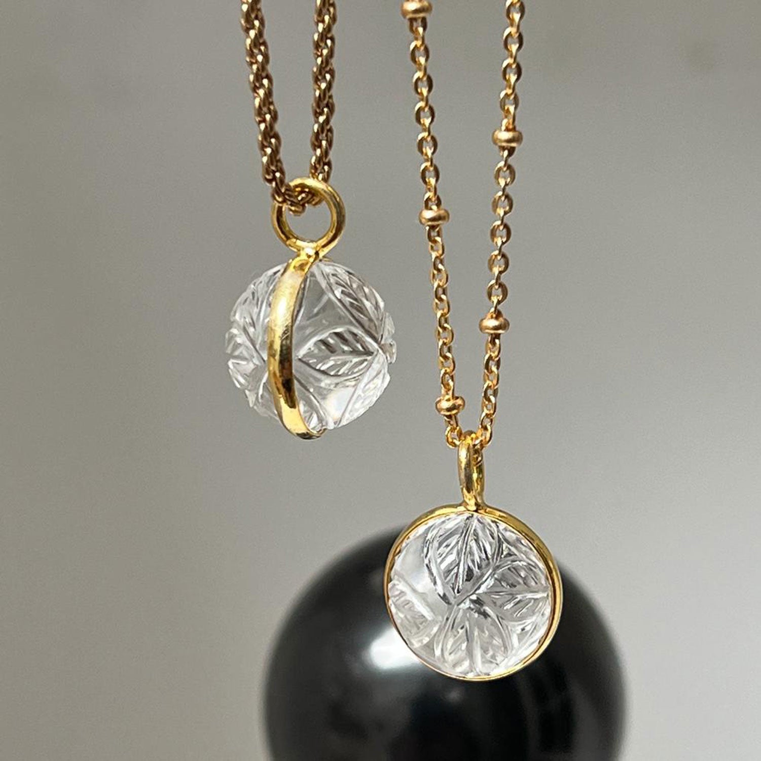 Two Hand-carved rock crystal pendants with four carved leaves on 22ct gold-plated different chains