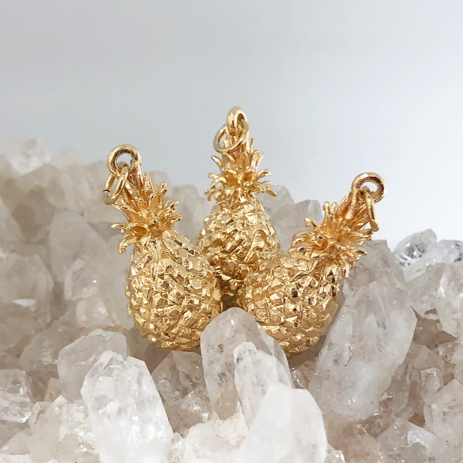 Three Pineapple Charm Pendantson a bed of crystals
