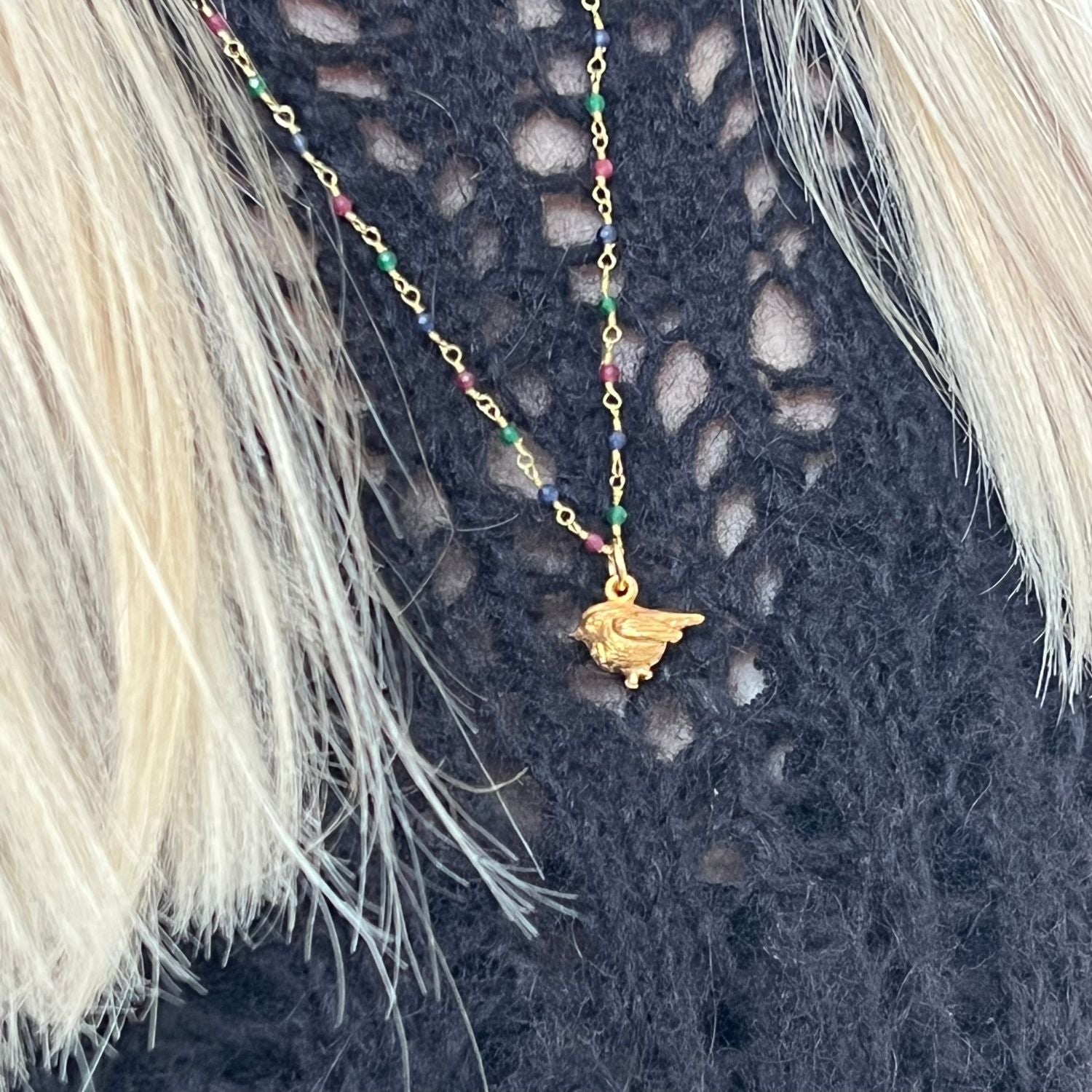 22ct Gold Plated Rosary necklace with Ruby, Saphhire and Emerald. Complete with a Robin charm. Worn on a blue jumper